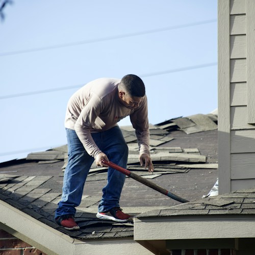 Roof repair, removing damaged shingles from residential roof