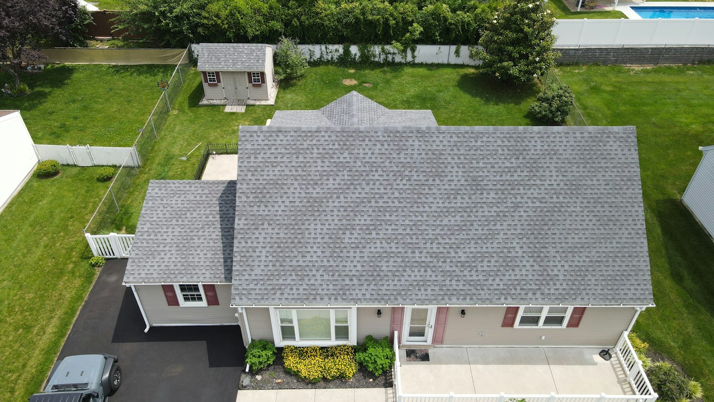 Aerial view of a completed grey shingled roof on a suburban DFW home
