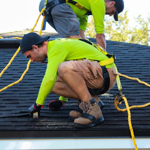Roof replacement in progress, crew installing new shingles